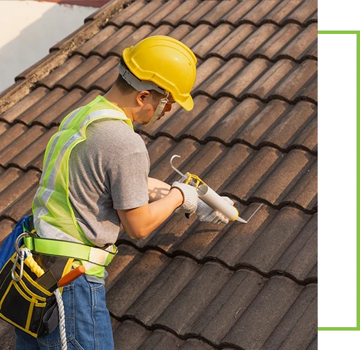 Worker man using silicone sealant adhesive to fix crack of the old tile roof.